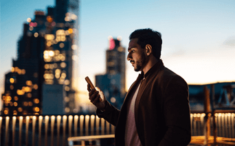 a man stands outside at sunset with his phone