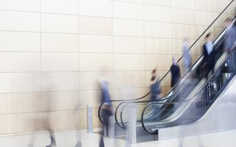 Employees walking up an escalator in the foyer of an office building