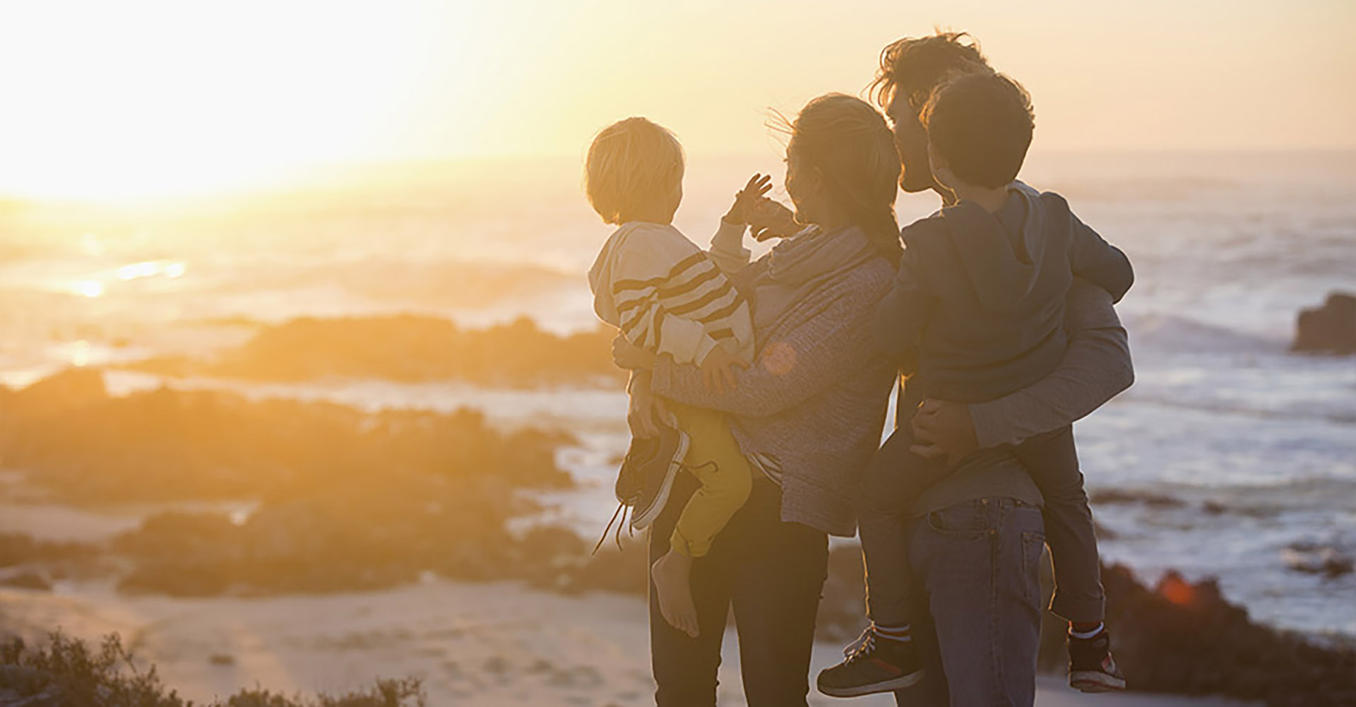 Family standing together on beach in sunset